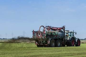 Fototapeta na wymiar Landwirtschaft Traktor mit großem Hänger beim Düngen