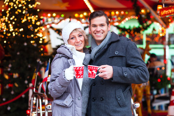 Pärchen trinkt Glühwein auf Weihnachtsmarkt im Advent