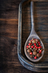 Peppercorns in old wooden spoon