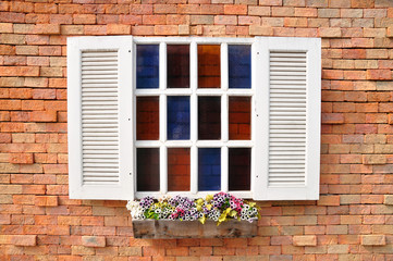White window on red brick wall and color glass hang flowers pot.