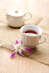 cup of tea with orchid flower on wooden table