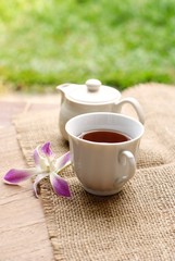 cup of tea with orchid flower on wooden table