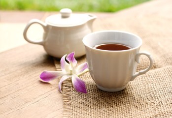 cup of tea with beautiful orchid over wooden background