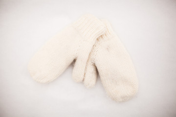 Soft warm knitted mittens on the white snow