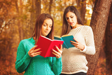 Girls reading books outdoors in park