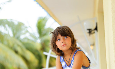 little girl sitting on the ballcony and looking at something