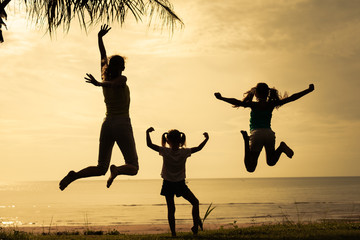 mother and  daughters jumping at the beach