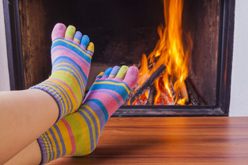  relaxing at fireplace in colorful funny toesocks - obrazy, fototapety, plakaty