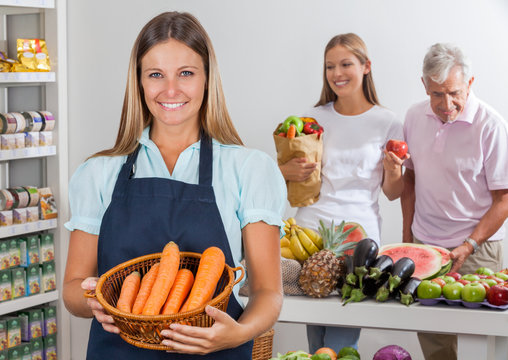 Saleswoman Holding Carrot Basket At Supermarket