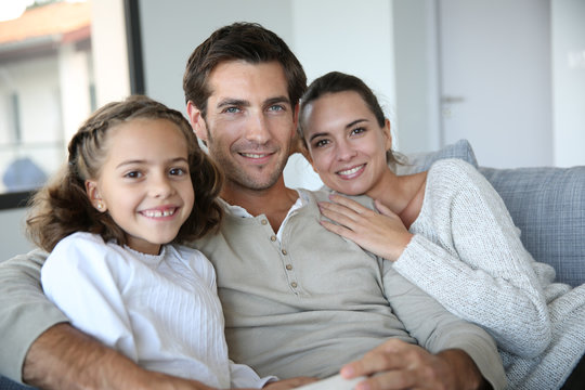 Cheerful family of three relaxing in sofa