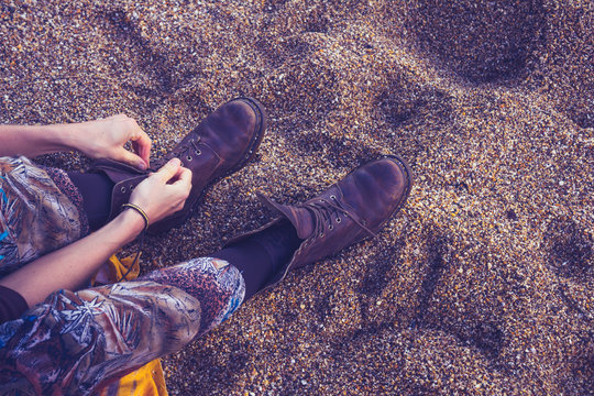 Woman Tying Her Boot Laces On The Beach