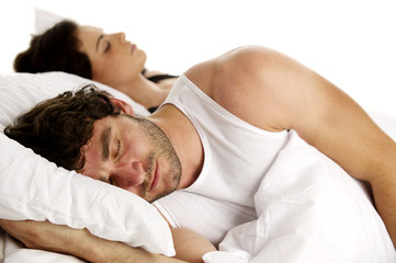 Obraz na płótnie Canvas Man laid in white bed next to a woman sleeping