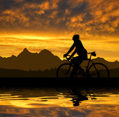 Obraz na płótnie Canvas silhouette of the cyclist on road bike at sunset