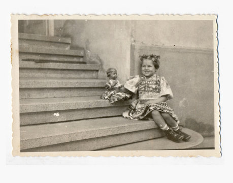 Little girl with doll on the stairs - circa 1950