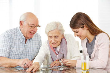 Zwei Senioren spielen ein Puzzle mit Enkelin