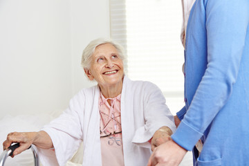 Krankenpflegerin hilft Seniorin beim Aufstehen