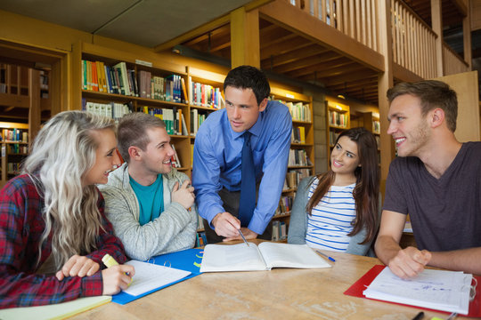 Lecturer explaining something to happy group of students