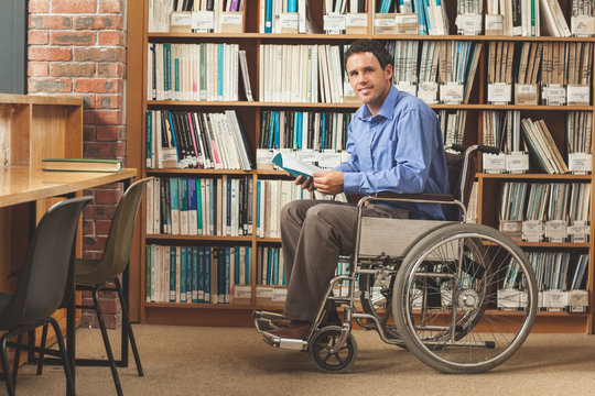 Happy man sitting in wheelchair holding a book