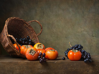 Still life with persimmons and grapes on the table © Marta Teron