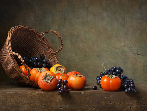 Still life with persimmons and grapes on the table