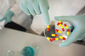 Extreme close up of scientist holding a petri dish filled with pills