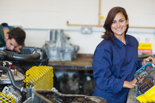 Smiling trainee repairing engine