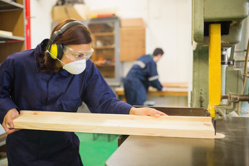 Serious trainee wearing safety protection using a saw