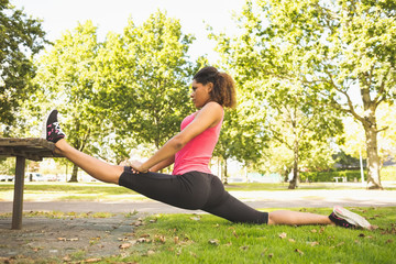Flexible young woman doing the splits exercise in park