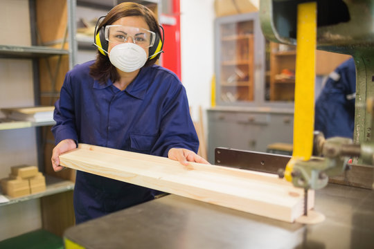 Apprentice wearing safety protection using saw