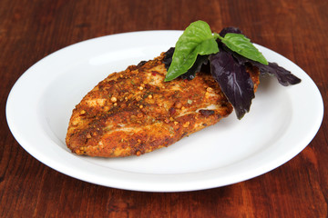 Roasted chicken fillets on white plate, on wooden background