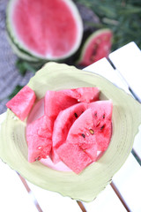 Watermelon slices on plate on table on grass background