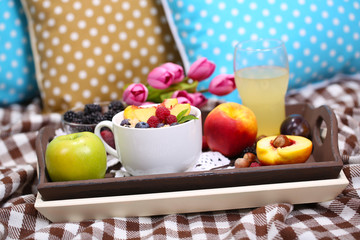 Oatmeal in plate with berries on napkins on wooden tray on bad