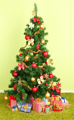 Decorated Christmas tree with gifts on green wall background