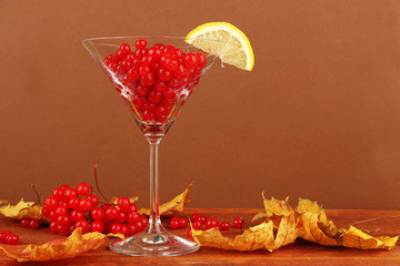Red berries of viburnum in glass and yellow leaves