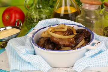 Fried chicken livers in pan on wooden table close-up
