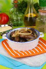 Fried chicken livers in pan on wooden table close-up
