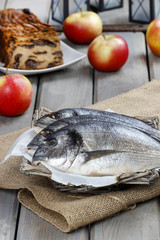 Gilt-head bream fishes in wicker basket on wooden table.