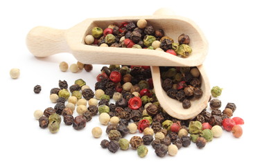 Colored pepper on a wooden spoons isolated on white background