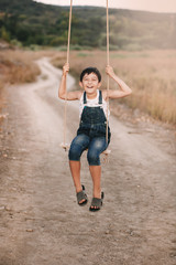 Happy young boy playing on swing in a park