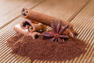 Ground coffee with cinnamon and star anise on a wooden backgroun