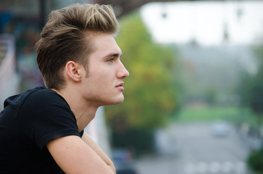 Profile  shot of attractive blond young man in city