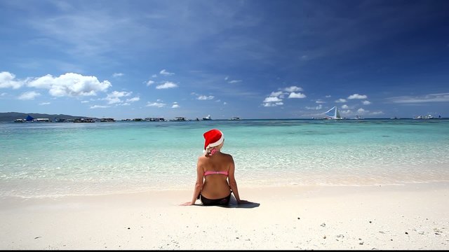 Woman in Santa Claus hat sitting on tropical beach, Boracay, Phi
