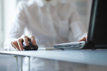 Woman's hand using cordless mouse on glass table