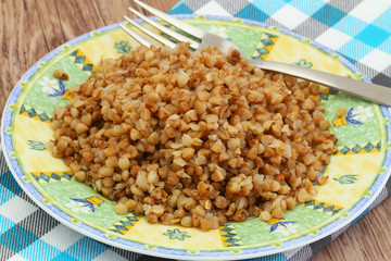 Cooked buckwheat on plate on checkered cloth