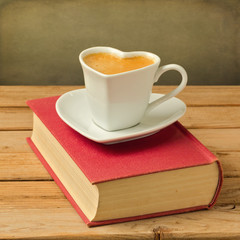 Coffee cup on book. Heart shape cup symbol of love