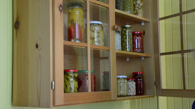 hand open wooden cupboards door puts jar canned garlic