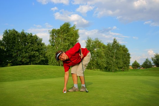 Golf, woman golfer taking out a ball from of hole