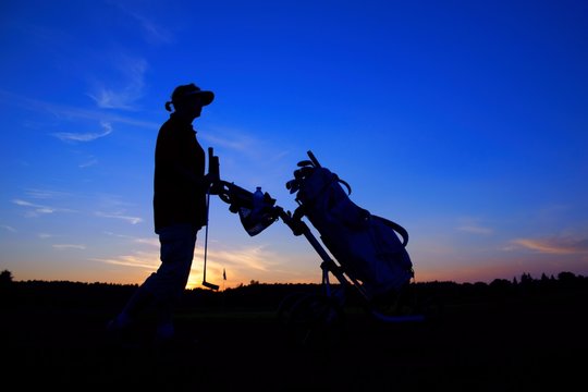 Golf, woman golfer with golf bag at sunset, as backgrounds