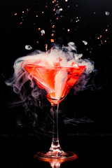 red cocktail with splash and ice vapor