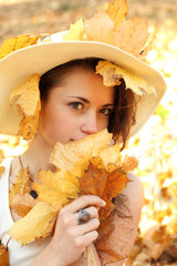 Piękna dziewczyna w kapeluszu i jesienne liście. - obrazy, fototapety, plakaty
